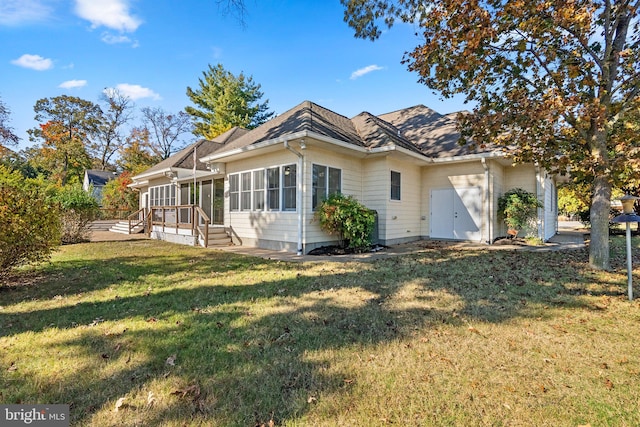 rear view of house featuring a sunroom and a yard