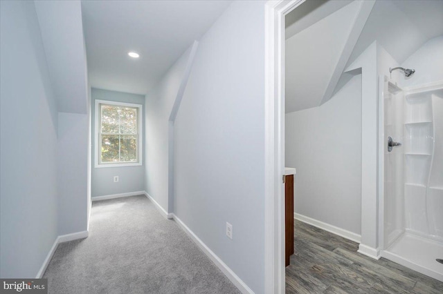 hallway with vaulted ceiling and baseboards