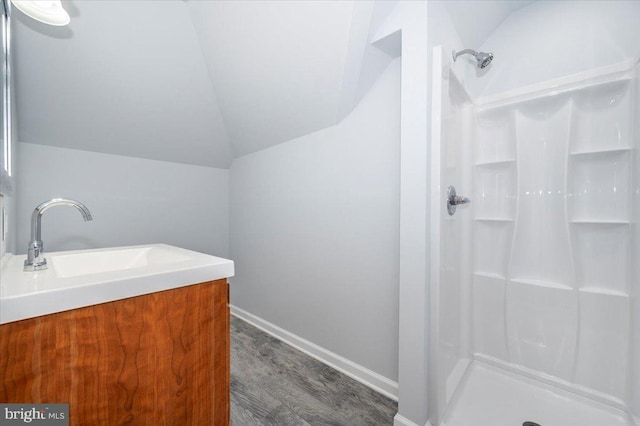 full bath featuring a stall shower, baseboards, wood finished floors, and lofted ceiling