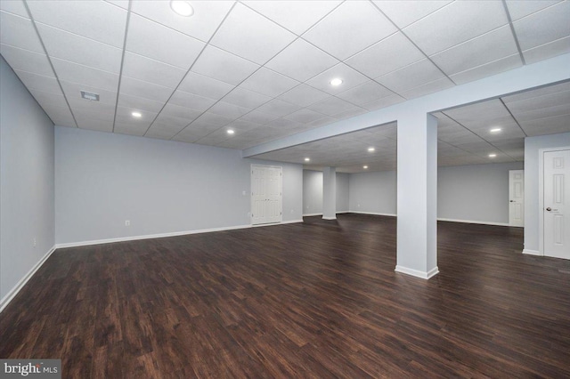 finished below grade area featuring recessed lighting, baseboards, dark wood-style floors, and a drop ceiling