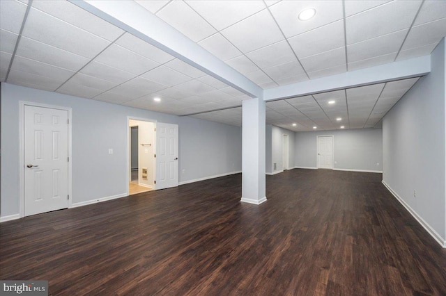 finished basement featuring wood finished floors, baseboards, and a paneled ceiling