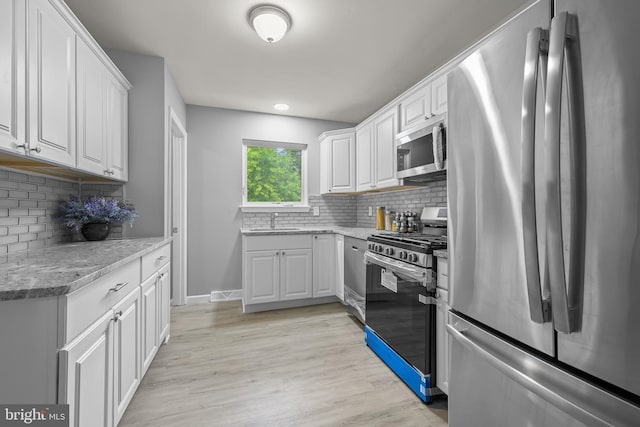 kitchen with appliances with stainless steel finishes, light wood-type flooring, and white cabinets