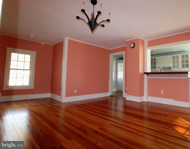 unfurnished living room featuring ornamental molding, wood-type flooring, and an inviting chandelier