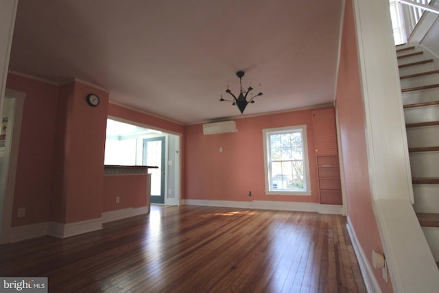 unfurnished living room featuring an inviting chandelier, an AC wall unit, crown molding, and dark hardwood / wood-style flooring