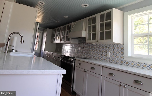 kitchen featuring custom exhaust hood, electric range, and white cabinets