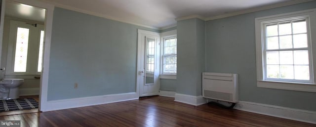 empty room featuring ornamental molding, heating unit, and dark hardwood / wood-style flooring