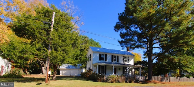 view of front facade featuring a chimney, covered porch, a front yard, fence, and a garage