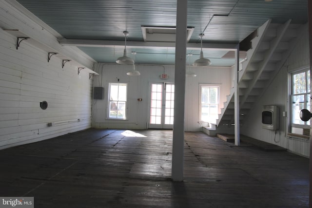 empty room featuring heating unit, dark hardwood / wood-style flooring, plenty of natural light, and wood walls