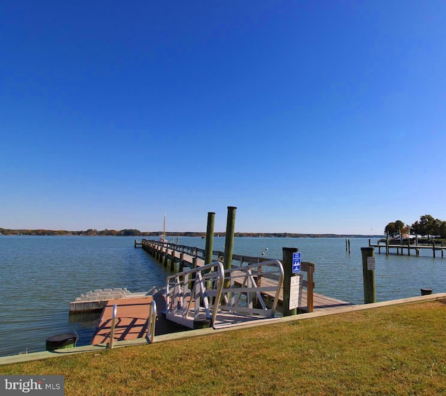 dock area with a lawn and a water view