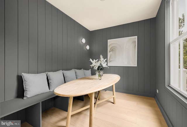 dining area with breakfast area, light hardwood / wood-style flooring, and wood walls