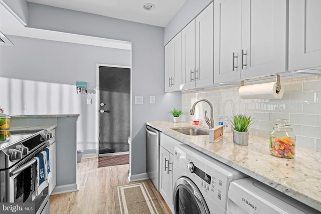 kitchen featuring washer / dryer, sink, light hardwood / wood-style flooring, and white cabinetry