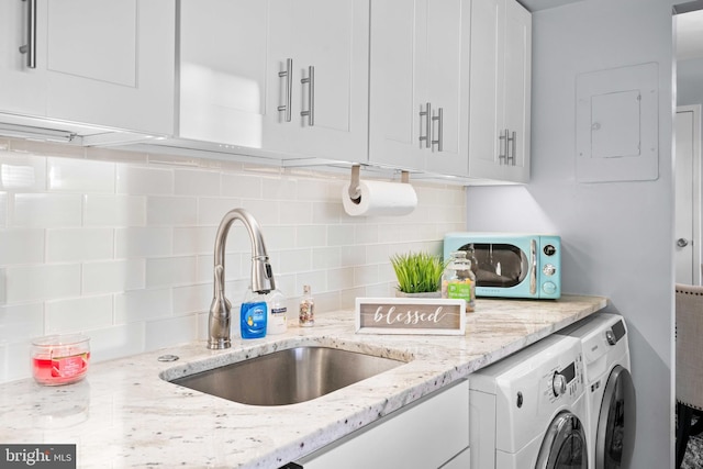 kitchen with washer and dryer, tasteful backsplash, sink, white cabinets, and light stone counters