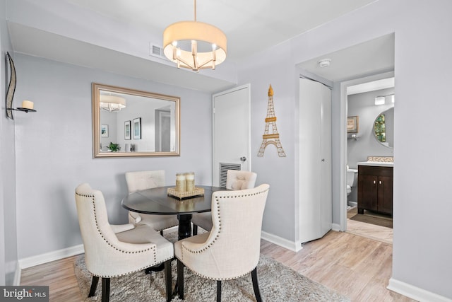 dining area with a notable chandelier and light hardwood / wood-style floors