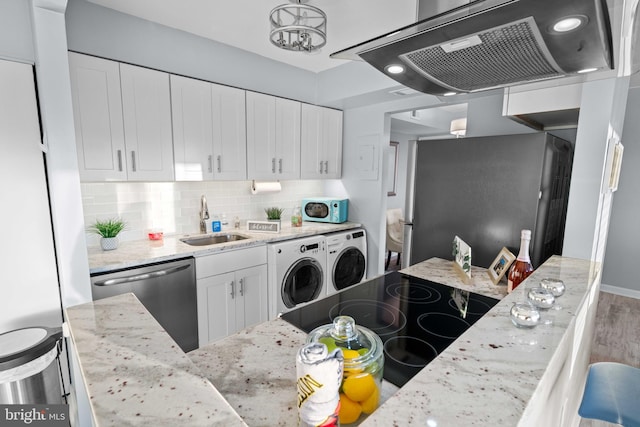 kitchen featuring exhaust hood, sink, white cabinets, appliances with stainless steel finishes, and washer and dryer