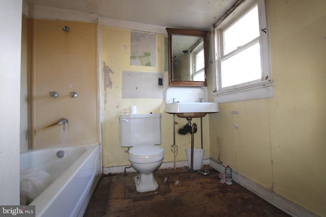 bathroom with a washtub, toilet, and sink