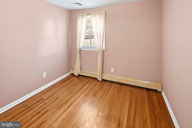 unfurnished room featuring a baseboard radiator and light hardwood / wood-style floors