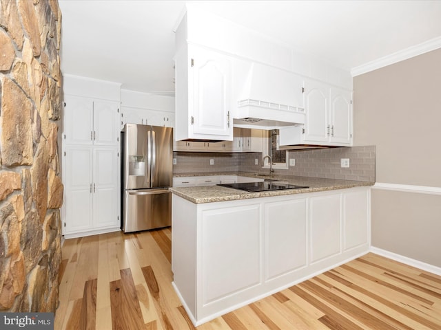 kitchen featuring kitchen peninsula, black electric stovetop, white cabinets, stainless steel fridge with ice dispenser, and light hardwood / wood-style floors