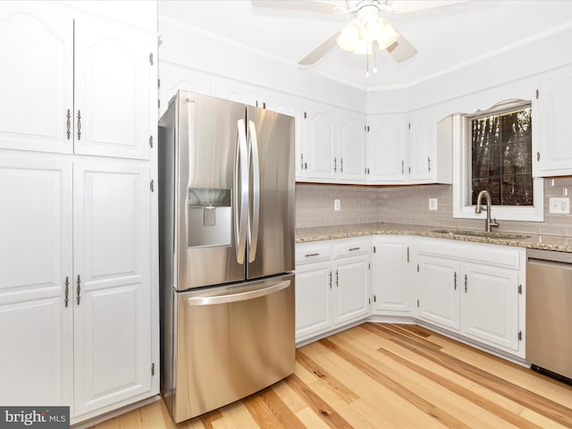 kitchen featuring sink, stainless steel appliances, light stone counters, light hardwood / wood-style floors, and white cabinets