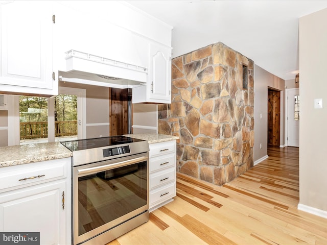 kitchen with white cabinets, light stone counters, stainless steel electric range oven, and light hardwood / wood-style flooring