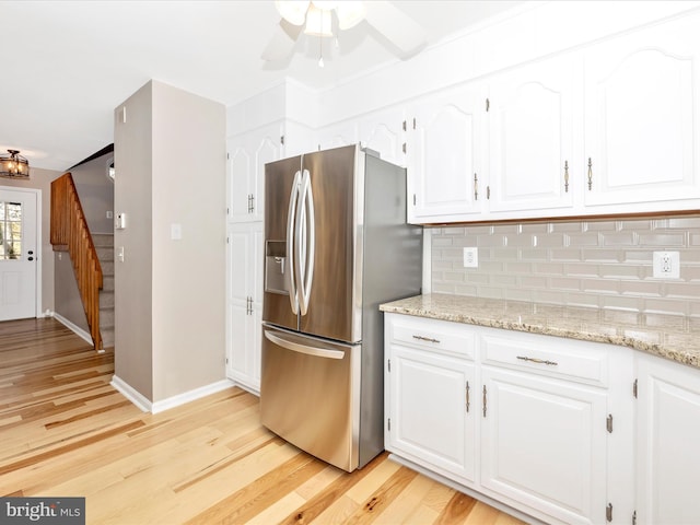 kitchen with white cabinetry, decorative backsplash, stainless steel fridge with ice dispenser, and light stone counters