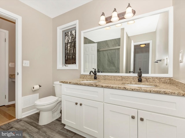 bathroom with hardwood / wood-style floors, vanity, toilet, and a shower with door