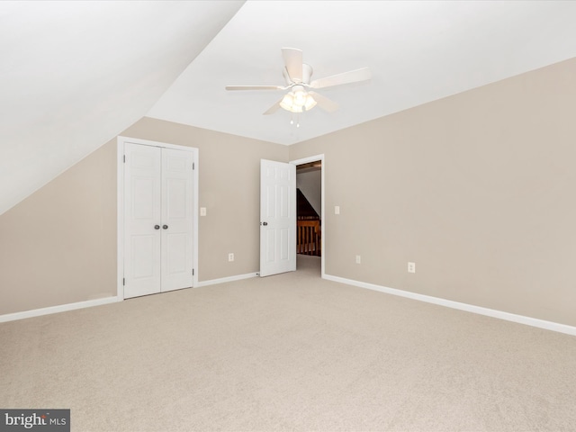 unfurnished bedroom featuring light carpet, a closet, ceiling fan, and lofted ceiling