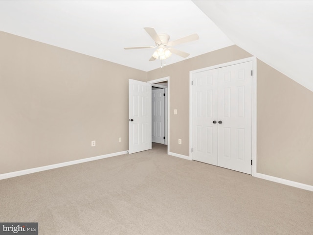 unfurnished bedroom with ceiling fan, a closet, light colored carpet, and vaulted ceiling