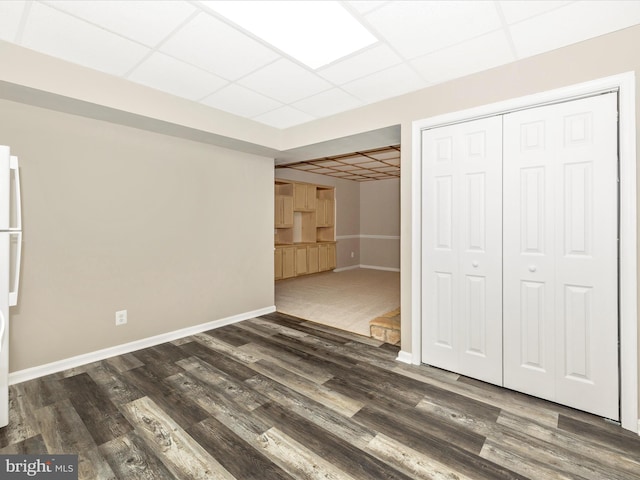 basement with a drop ceiling and dark hardwood / wood-style floors