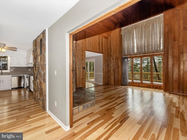 unfurnished living room featuring ceiling fan, light hardwood / wood-style flooring, a healthy amount of sunlight, and vaulted ceiling