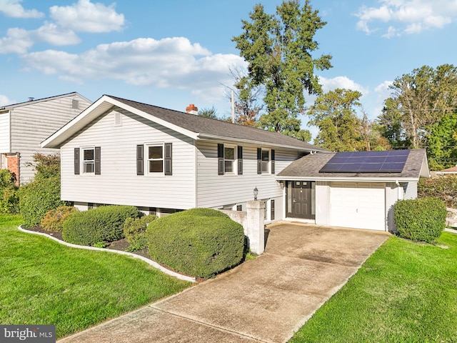 view of front of house featuring a garage, a front lawn, and solar panels