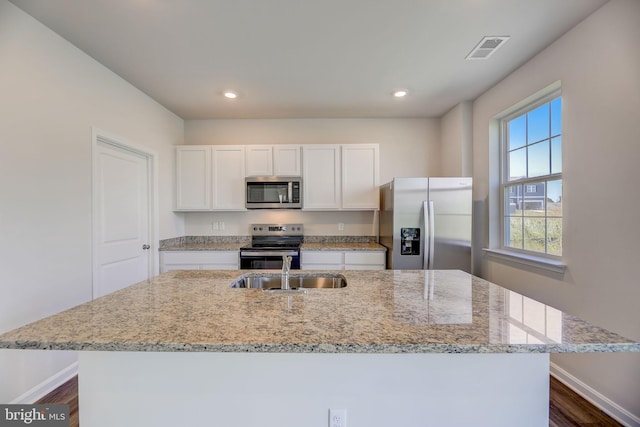 kitchen featuring sink, stainless steel appliances, white cabinets, dark wood-type flooring, and a center island with sink