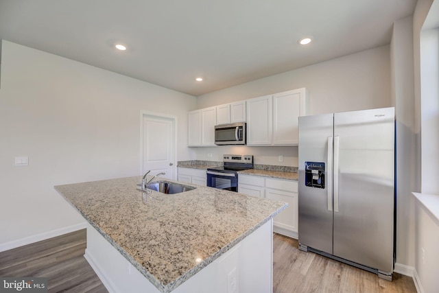 kitchen with white cabinetry, appliances with stainless steel finishes, sink, and a center island with sink