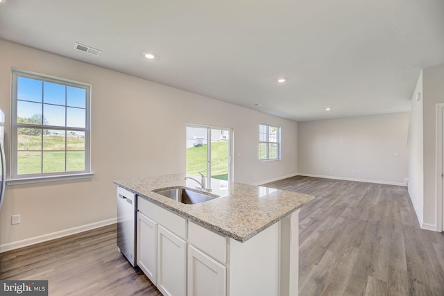 kitchen with white cabinetry, light hardwood / wood-style floors, dishwasher, and a center island with sink