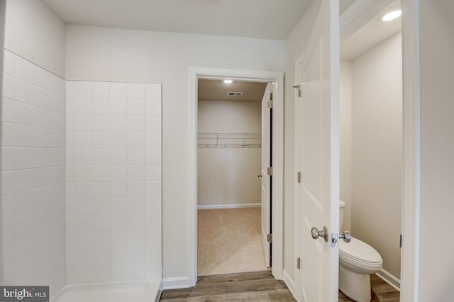 bathroom with toilet, wood-type flooring, and walk in shower