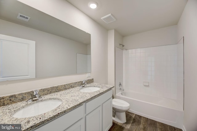 full bathroom featuring tiled shower / bath, vanity, wood-type flooring, and toilet