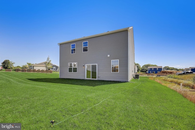 rear view of property with central air condition unit and a lawn