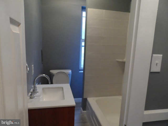 bathroom with a tub, vanity, and toilet