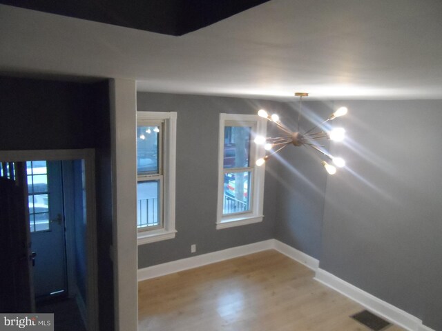 empty room featuring light wood-type flooring and an inviting chandelier