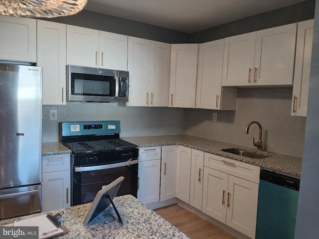 kitchen with stainless steel appliances, white cabinetry, and sink