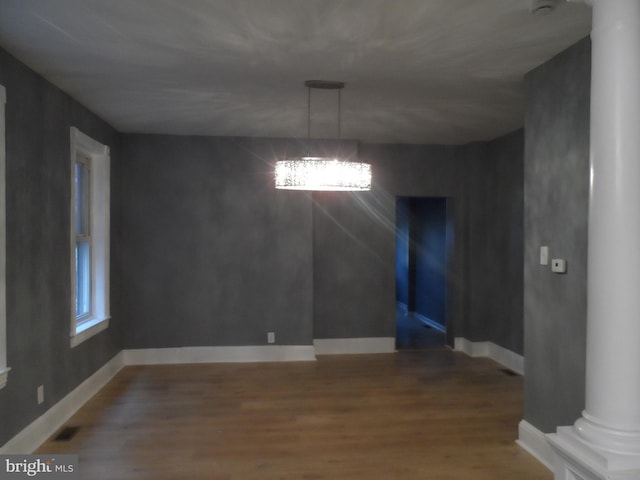 unfurnished dining area with wood-type flooring and ornate columns