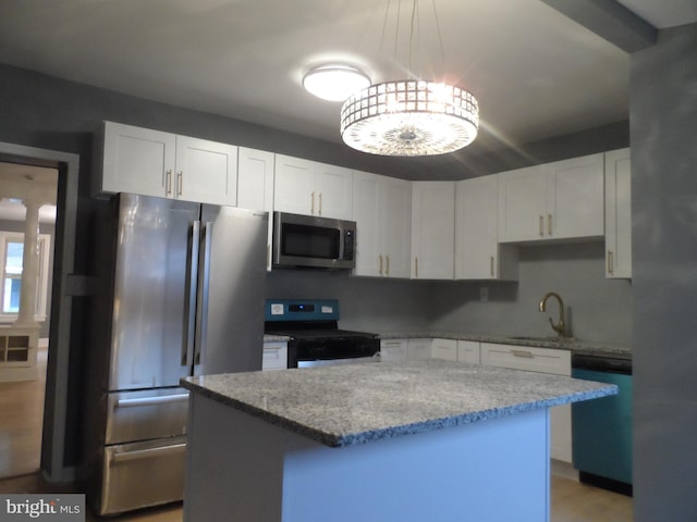 kitchen with white cabinets, sink, hanging light fixtures, appliances with stainless steel finishes, and a kitchen island