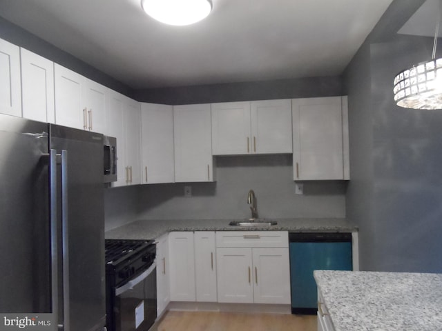 kitchen featuring light stone countertops, white cabinetry, sink, stainless steel appliances, and light hardwood / wood-style flooring