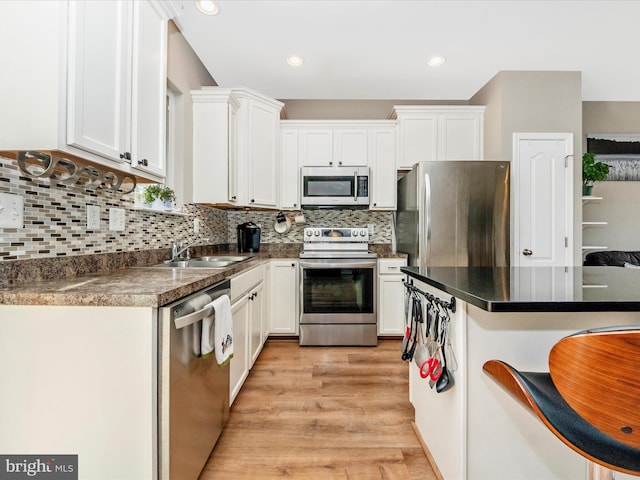 kitchen featuring white cabinetry, tasteful backsplash, appliances with stainless steel finishes, and light hardwood / wood-style flooring