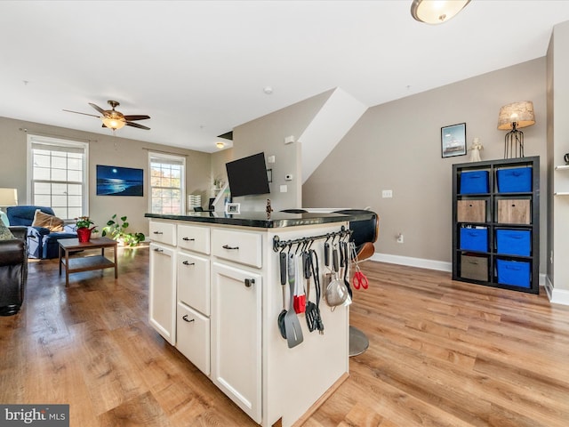 kitchen featuring white cabinets, ceiling fan, light wood-type flooring, and a kitchen island