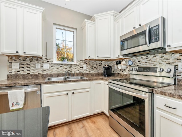 kitchen with tasteful backsplash, sink, light wood-type flooring, white cabinetry, and stainless steel appliances