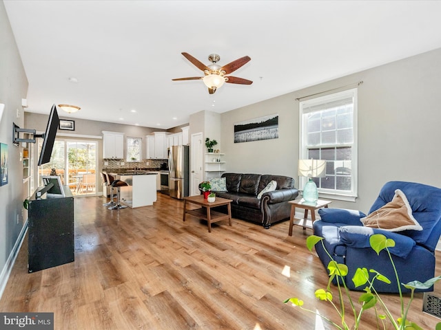 living room with light hardwood / wood-style floors and ceiling fan