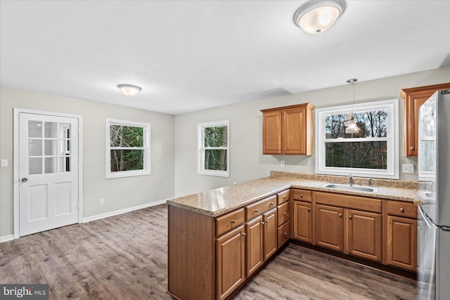 kitchen featuring kitchen peninsula, hardwood / wood-style floors, stainless steel refrigerator, and sink