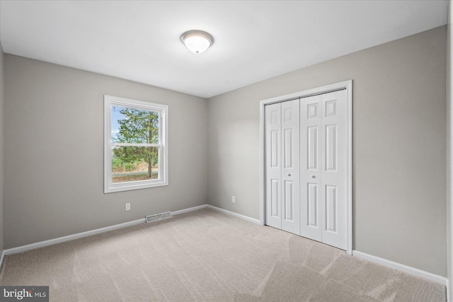 unfurnished bedroom featuring a closet and light colored carpet