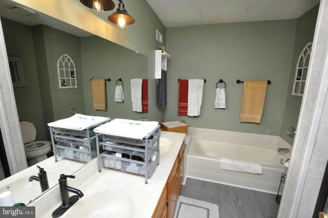 bathroom with vanity, hardwood / wood-style flooring, toilet, and a bathing tub