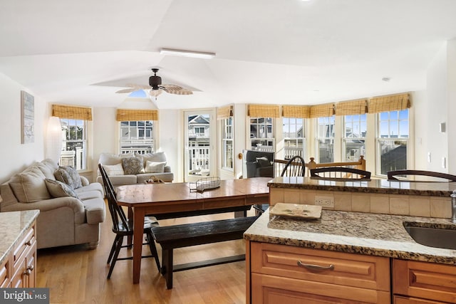 kitchen featuring light stone countertops, sink, light hardwood / wood-style floors, ceiling fan, and lofted ceiling